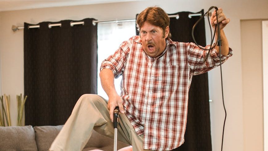 Man vacuuming a carpet doing a funny dance or tripping over the cord