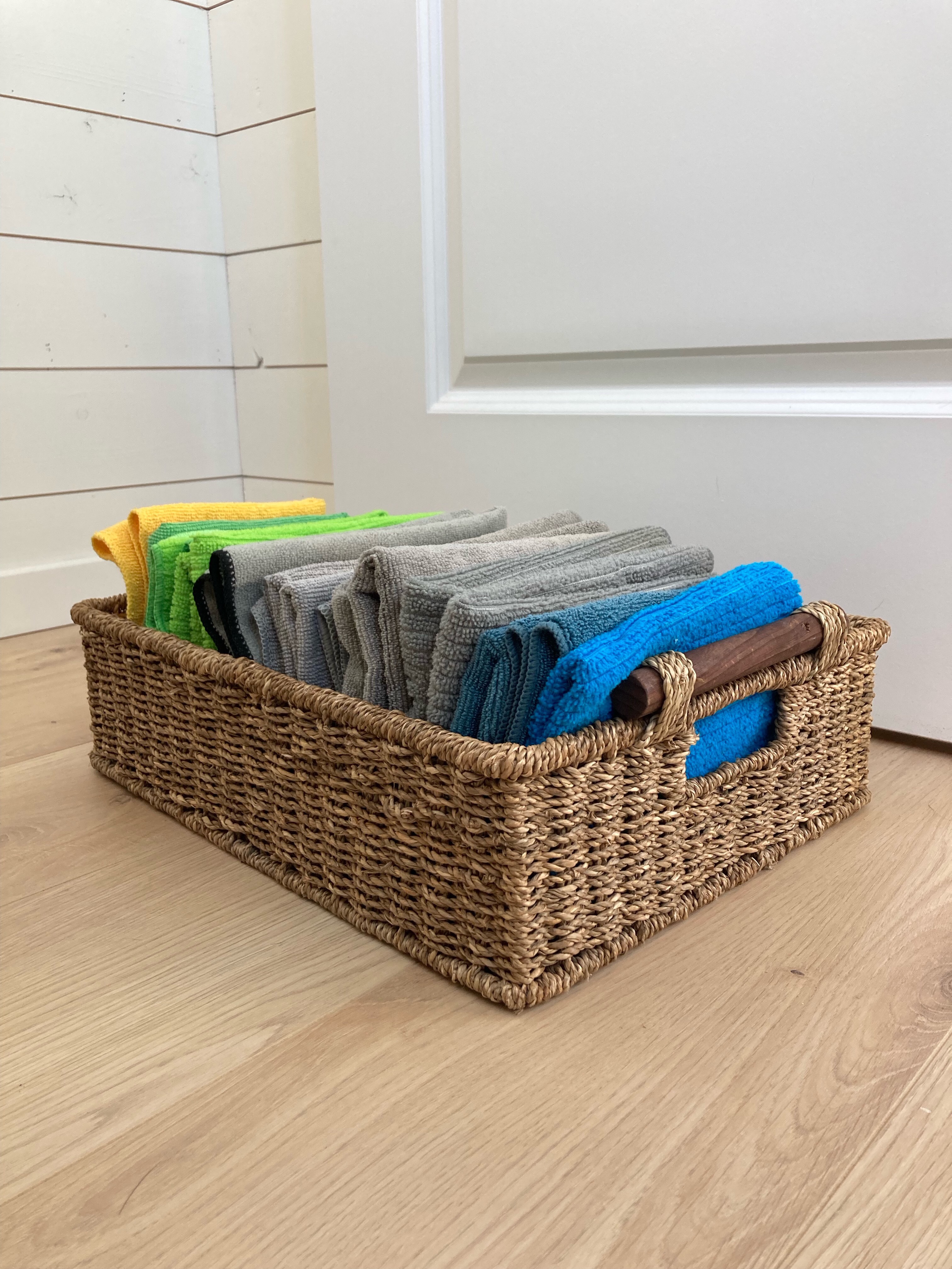 colourful microfibre cloths sitting neatly folded in a wicker basket and organised by colour