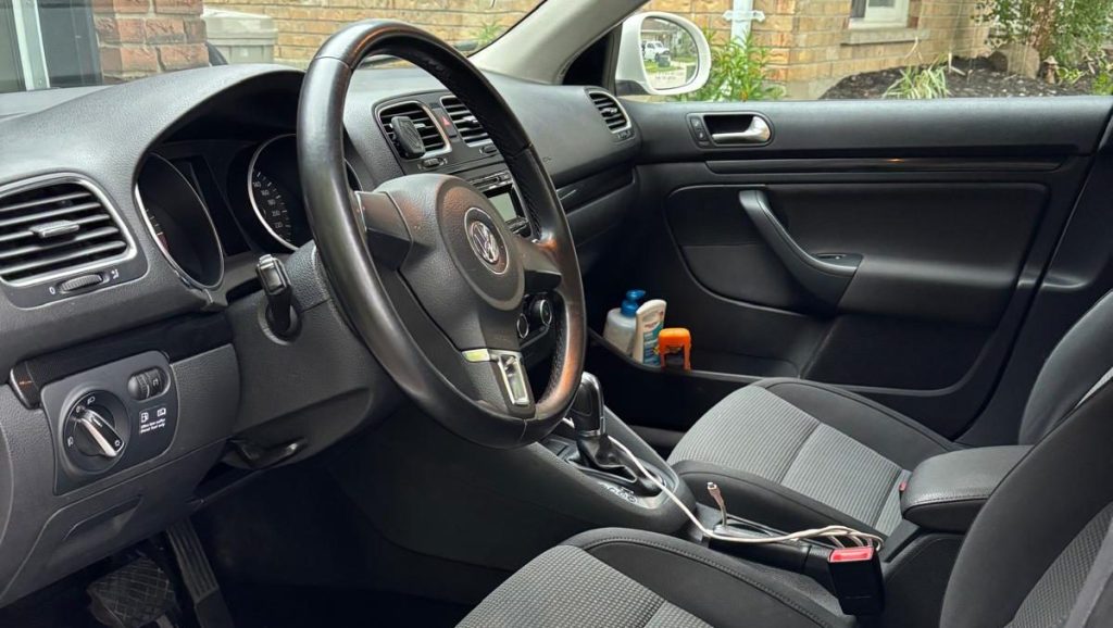 Looking into a car from the driver's door, with vacuumed and carpet cleaned seats and carpets and carefully sprayed and wiped dashboard