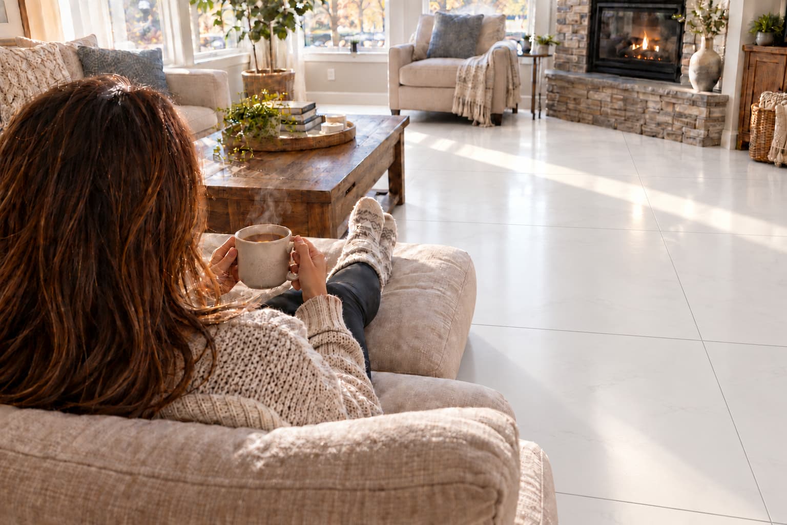 Woman sitting enjoying a coffee in a living room with large white tiles